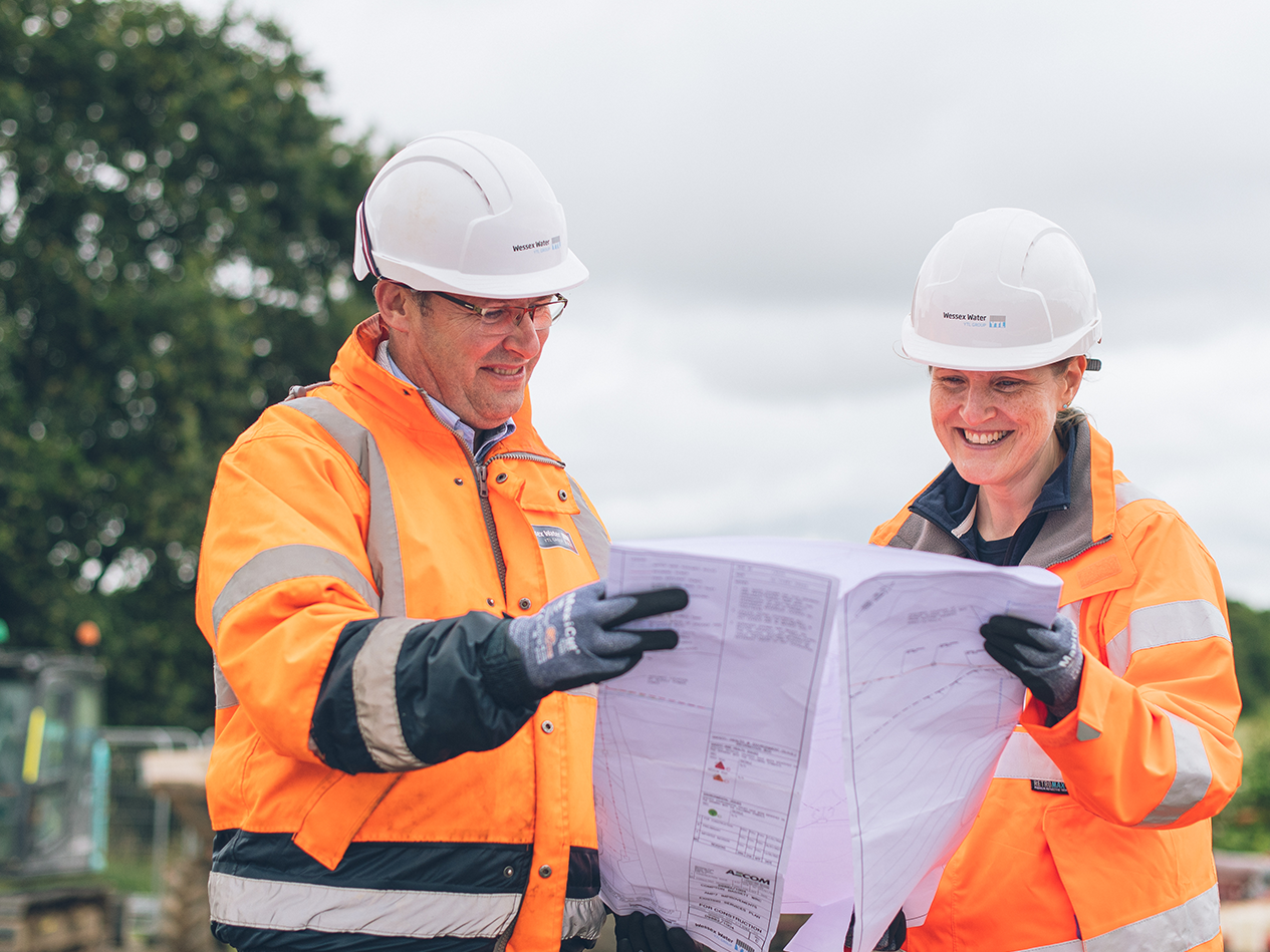 Two Wessex Water construction workers on site looking at a set of plans together in PPE